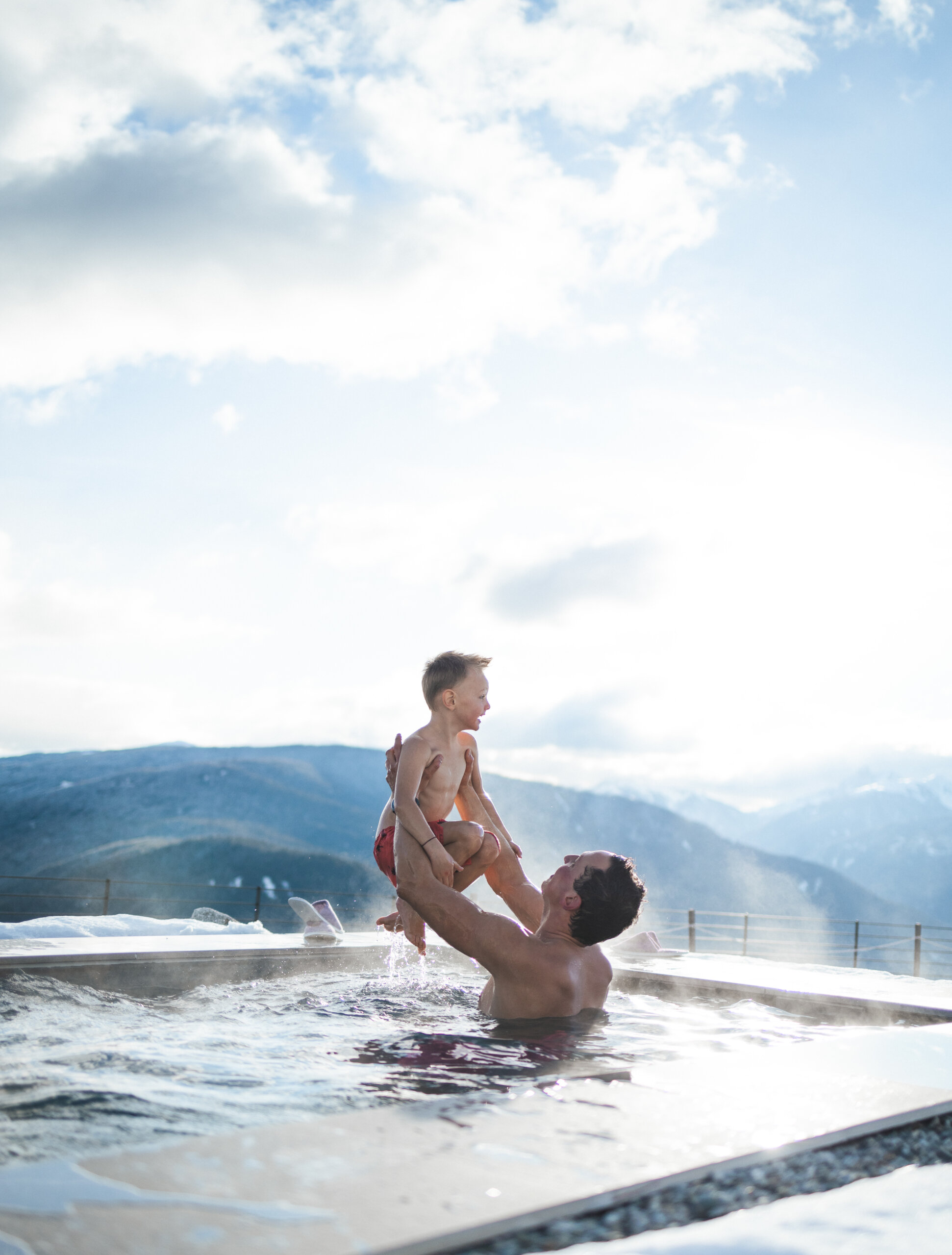 Vater hebt seinen Sohn im Pool in die Luft - Hotel Familiamus